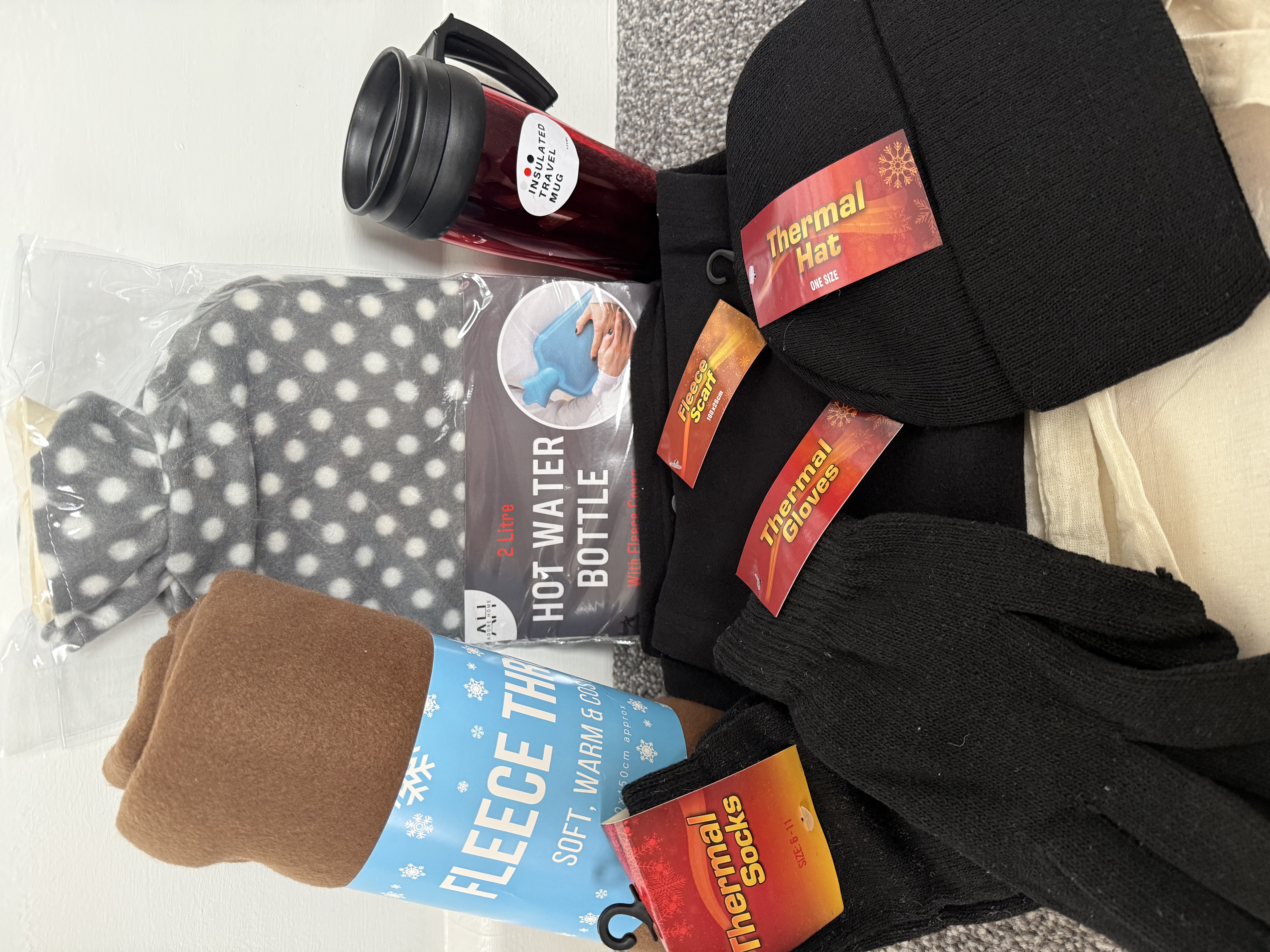 A photo of the winter warmer pack described in the text. The hot water bottle has a grey polka dot pattern and the fleece blanket is brown