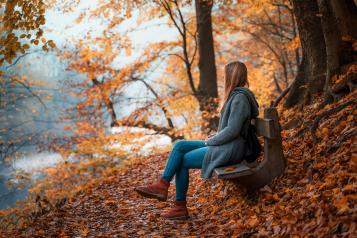 lady sat on a bench in an autumn scene