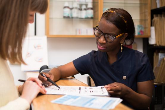A receptionist helping a lady to fill out a form A receptionist helping a lady to fill out a form