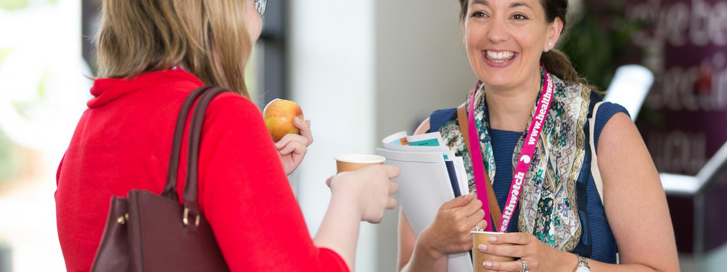Healthwatch staff members at a conference wearing branded lanyards
